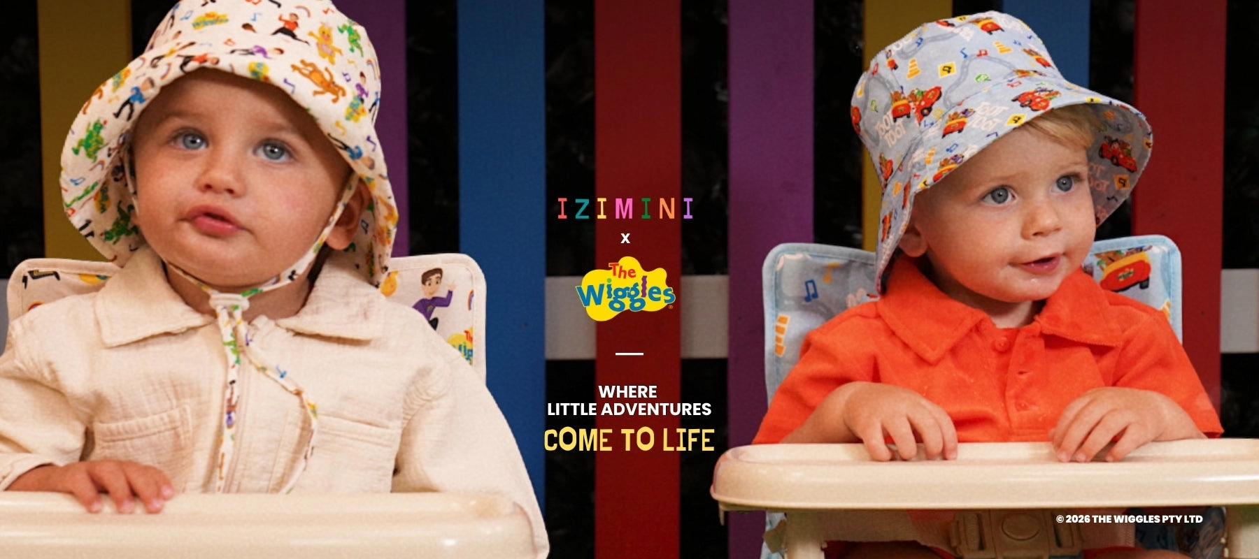 Two babies in IZIMINI hats against a rainbow-striped backdrop